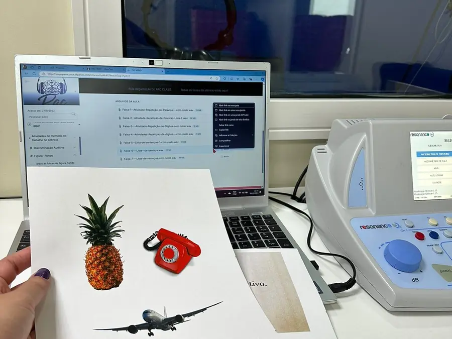 Atividade aberta no notebook ao lado do audiômetro, com as figuras impressas na bancada